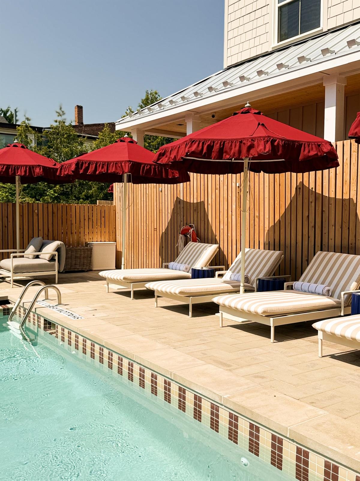 Poolside loungers and red umbrellas at Leeward House